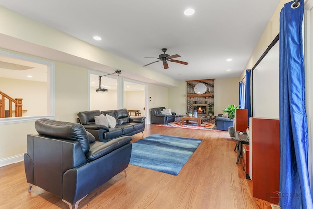 living area featuring a ceiling fan, wood finished floors, a fireplace, stairway, and recessed lighting