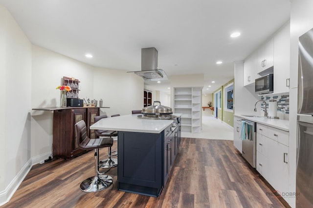 kitchen with island exhaust hood, dark wood finished floors, stainless steel appliances, white cabinets, and recessed lighting