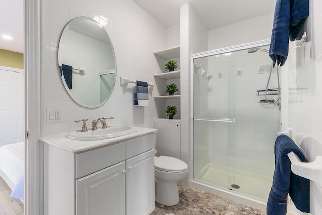 bathroom featuring tile walls, a shower stall, toilet, and vanity