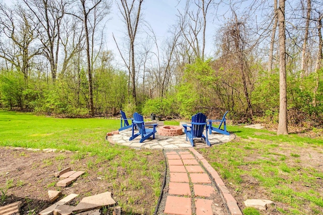 view of green lawn with a fire pit and a patio area