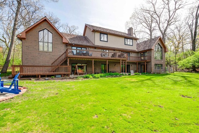 back of house featuring a chimney, a wooden deck, a lawn, and brick siding