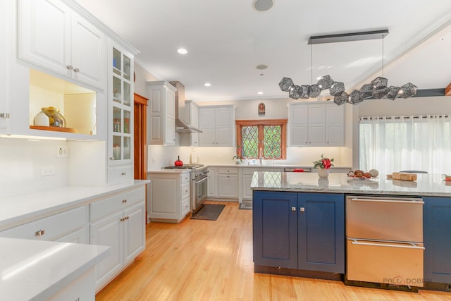 kitchen with high end stainless steel range, wall chimney exhaust hood, white cabinetry, light wood finished floors, and glass insert cabinets