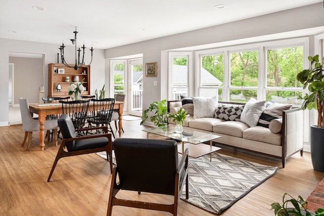 living room with recessed lighting, an inviting chandelier, and light wood-style flooring
