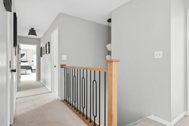 corridor with carpet floors, baseboards, and an upstairs landing