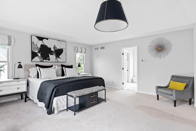 carpeted bedroom with baseboards, visible vents, multiple windows, and ensuite bathroom