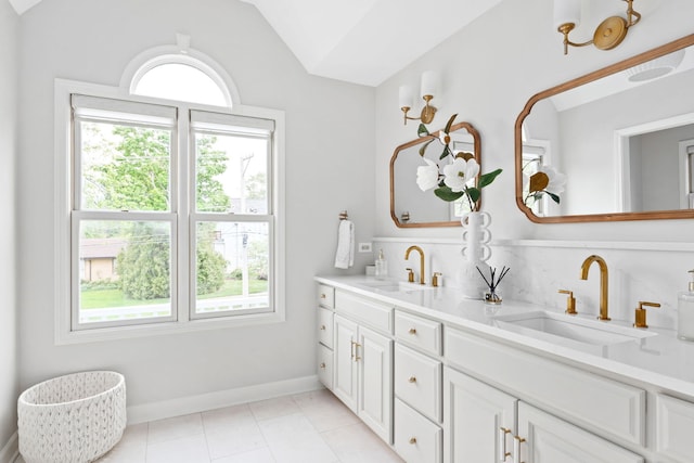 full bathroom featuring double vanity, a sink, lofted ceiling, and tile patterned flooring