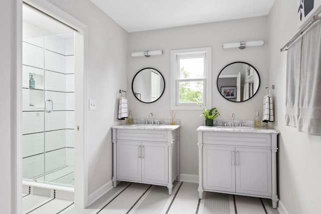 full bath with a sink, baseboards, a stall shower, and two vanities