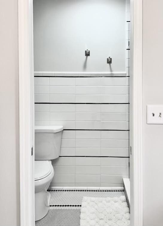 bathroom with tile patterned floors, toilet, and tile walls