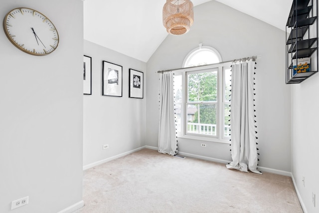 carpeted spare room with baseboards, visible vents, and lofted ceiling