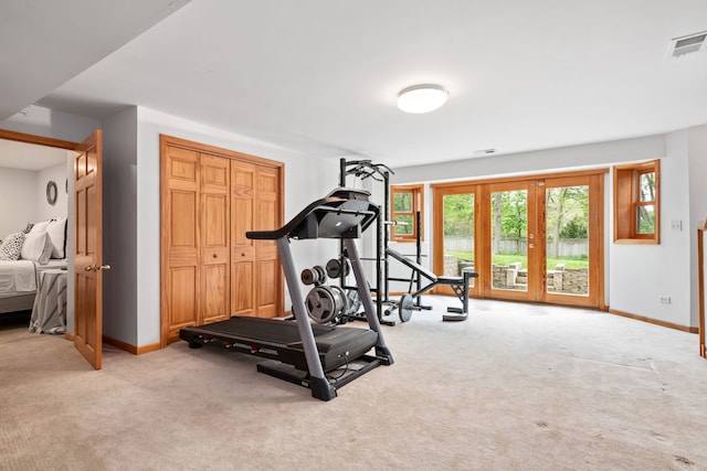 exercise room with baseboards, light colored carpet, and visible vents