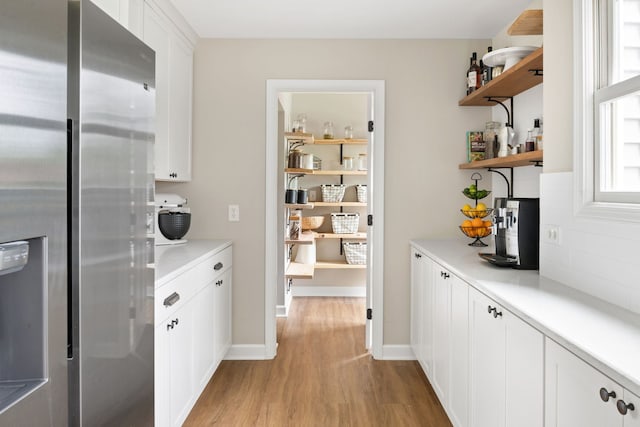 interior space with baseboards, light wood finished floors, backsplash, and stainless steel fridge with ice dispenser