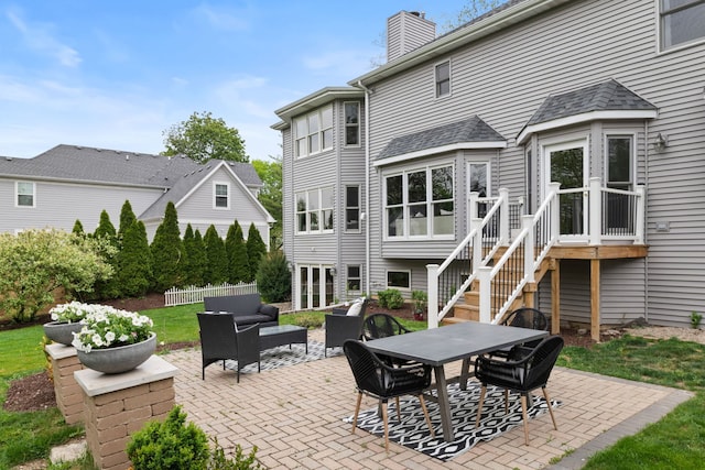 rear view of property featuring outdoor dining space, a patio, a chimney, and outdoor lounge area