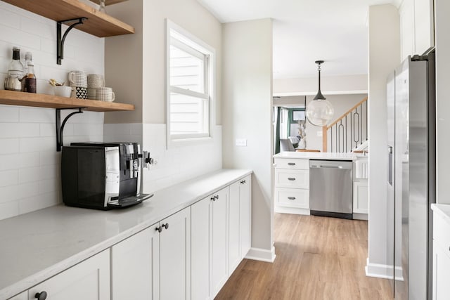 bar with decorative backsplash, baseboards, light wood-type flooring, hanging light fixtures, and stainless steel appliances
