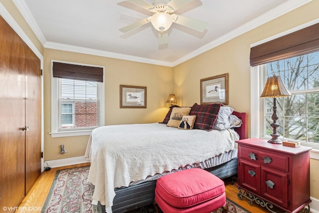 bedroom featuring light wood-type flooring, ceiling fan, baseboards, and ornamental molding