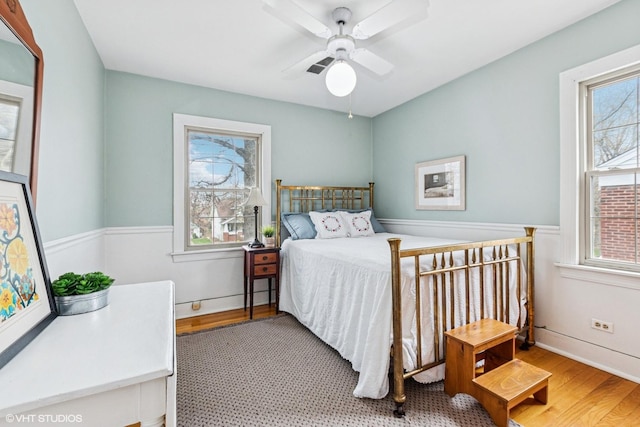 bedroom featuring ceiling fan, multiple windows, and wood finished floors