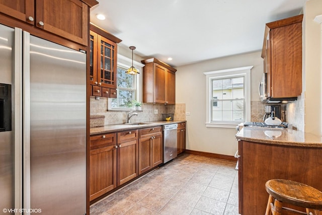 kitchen with stainless steel appliances, baseboards, brown cabinetry, and decorative backsplash