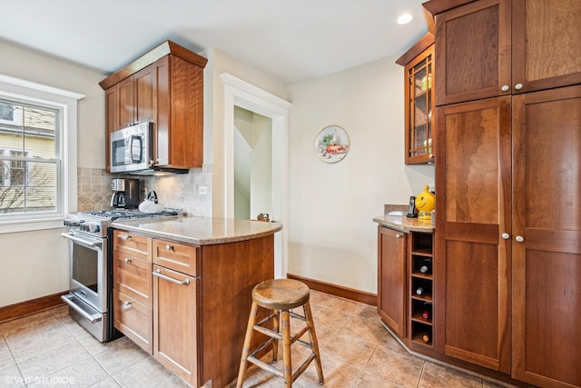 kitchen featuring tasteful backsplash, baseboards, light tile patterned flooring, and appliances with stainless steel finishes