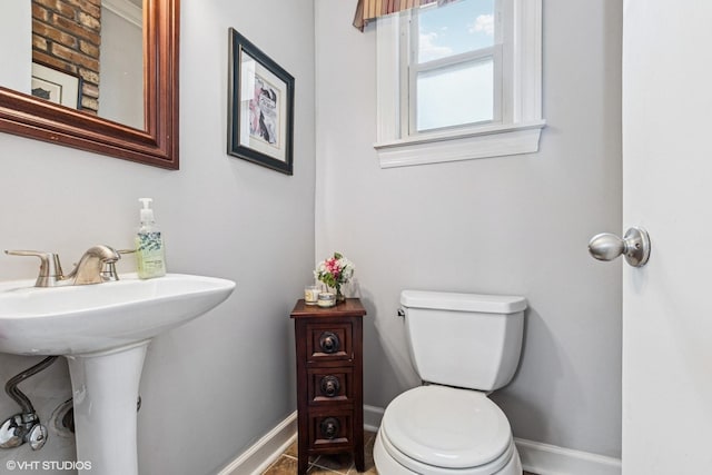 half bath featuring baseboards and toilet
