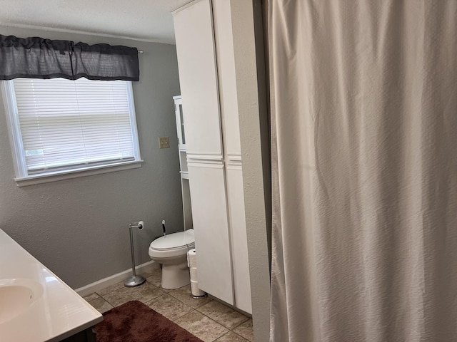 full bathroom featuring toilet, vanity, baseboards, and tile patterned flooring