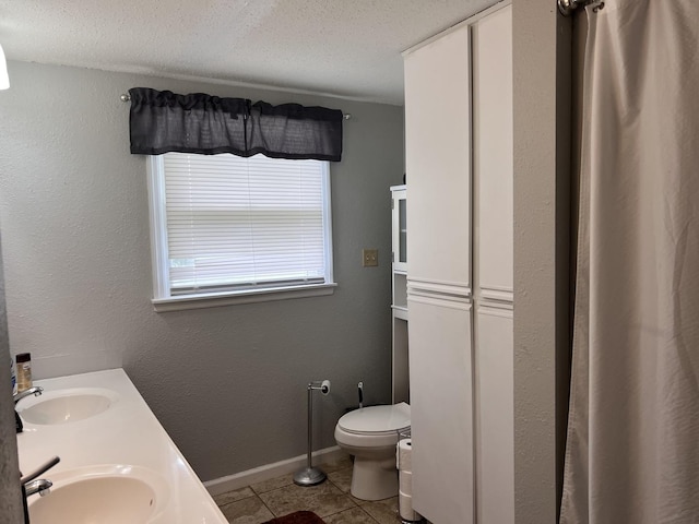 full bath with tile patterned floors, a textured ceiling, a sink, and toilet