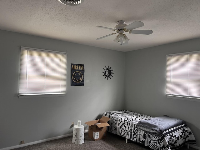 bedroom with a textured ceiling, multiple windows, and carpet floors