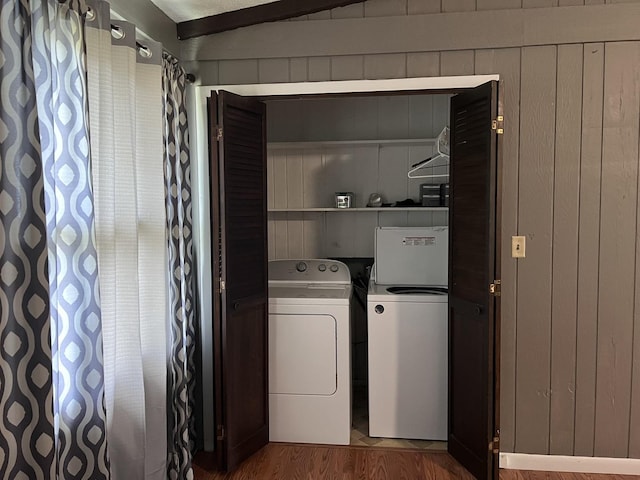 laundry area featuring wood walls, washing machine and dryer, laundry area, and wood finished floors