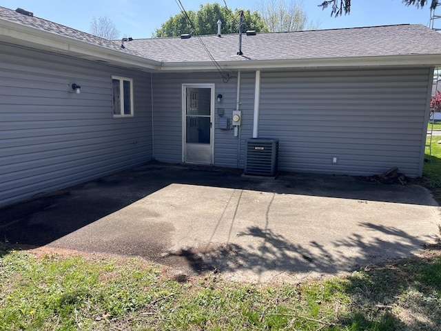 rear view of property with roof with shingles, a patio area, and central AC