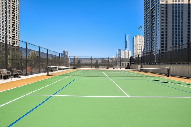 view of tennis court featuring a view of city and fence