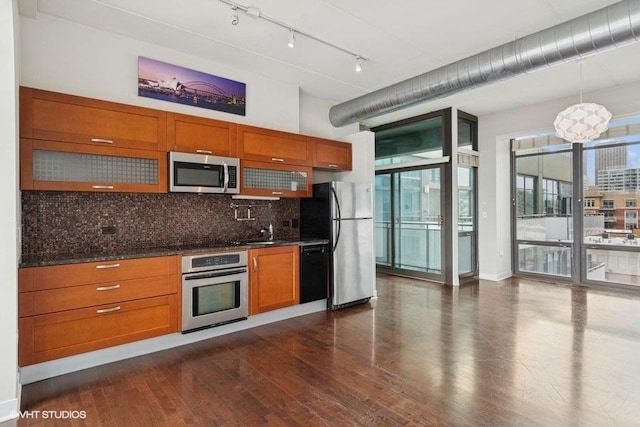 kitchen featuring brown cabinetry, dark wood-style flooring, backsplash, and stainless steel appliances