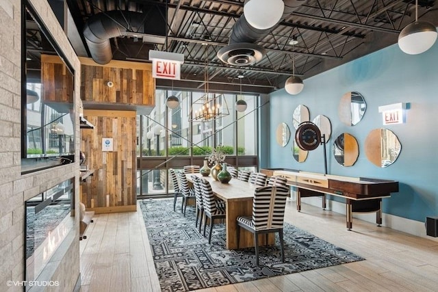 dining area featuring a notable chandelier, a glass covered fireplace, a wealth of natural light, and hardwood / wood-style floors
