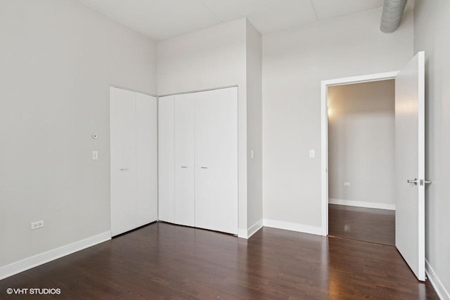unfurnished bedroom featuring baseboards, a closet, and wood finished floors