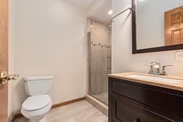 bathroom featuring toilet, a shower stall, vanity, and baseboards