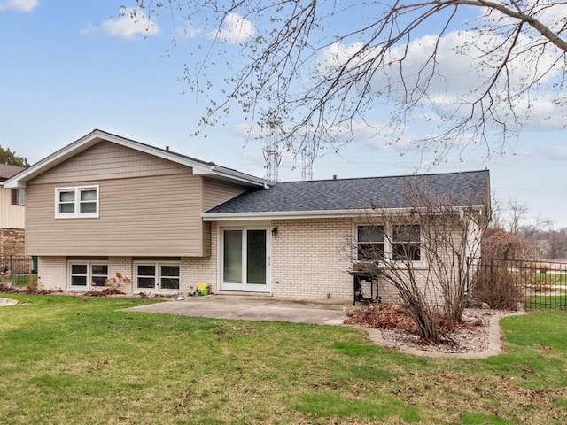 rear view of house with brick siding, fence, a patio, and a lawn