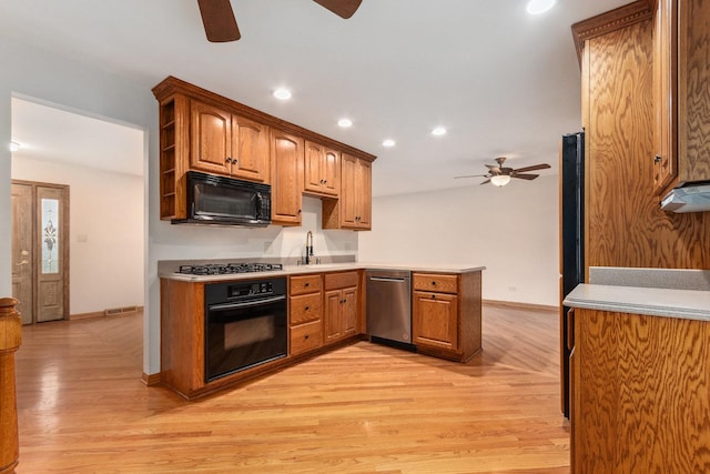 kitchen featuring a peninsula, baseboards, black appliances, and ceiling fan
