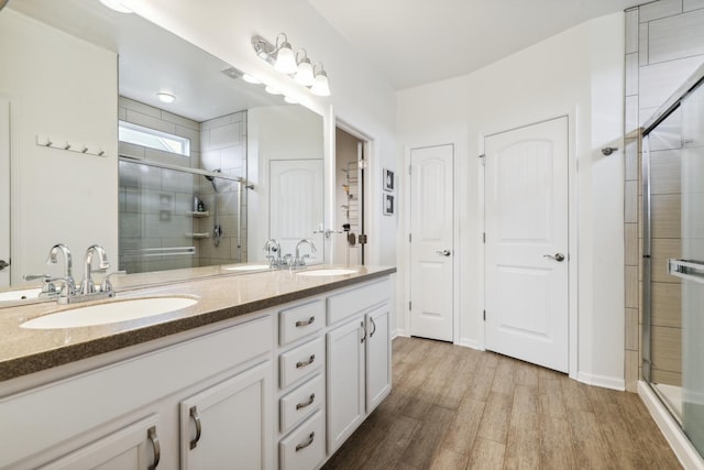 full bathroom with wood finished floors, a stall shower, and a sink