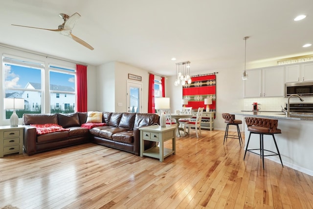 living area featuring recessed lighting, ceiling fan with notable chandelier, and light wood-type flooring