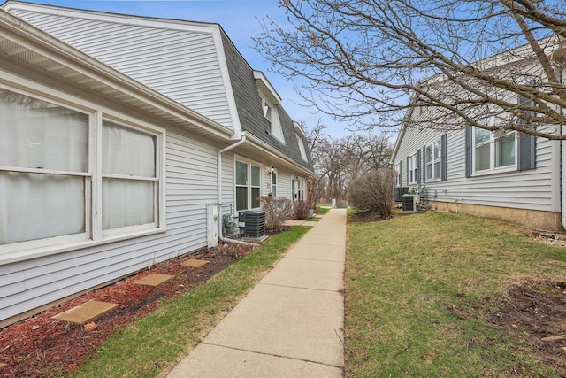 view of side of property with cooling unit, a yard, and a shingled roof