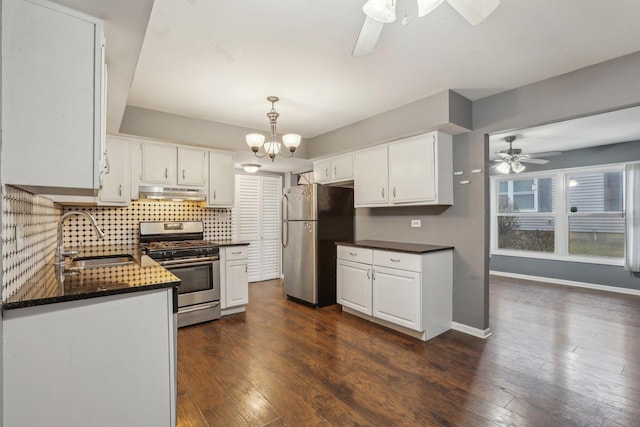 kitchen featuring under cabinet range hood, ceiling fan with notable chandelier, a sink, and stainless steel appliances
