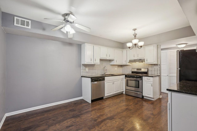 kitchen featuring backsplash, under cabinet range hood, visible vents, appliances with stainless steel finishes, and a sink