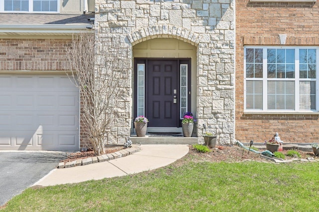 view of exterior entry featuring brick siding, roof with shingles, stone siding, and a garage