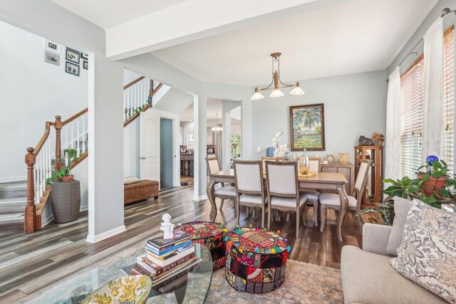 living room with a chandelier, wood finished floors, baseboards, and stairs
