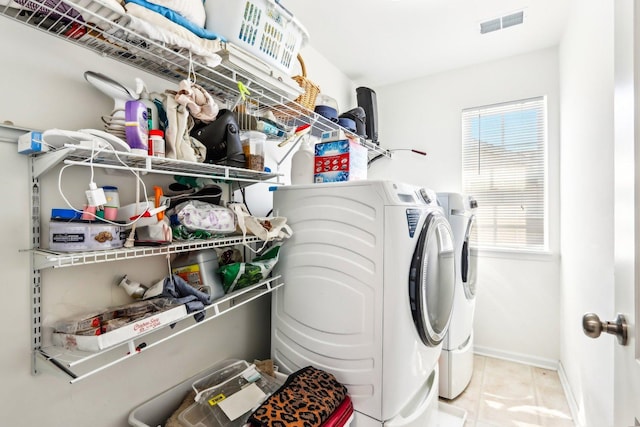 laundry room featuring washing machine and clothes dryer, tile patterned floors, baseboards, visible vents, and laundry area