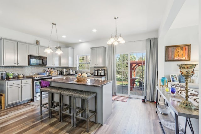 kitchen featuring black microwave, a wealth of natural light, stainless steel electric range, and gray cabinetry