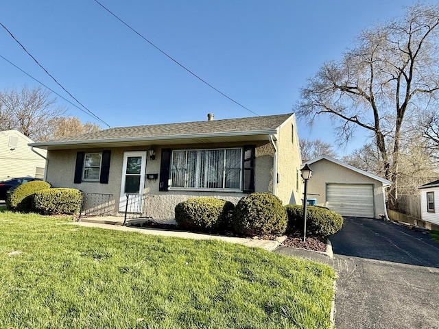view of front of house with stucco siding, an outdoor structure, a front yard, a garage, and driveway