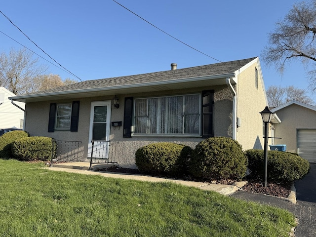 view of front of home with a front yard, roof with shingles, and stucco siding