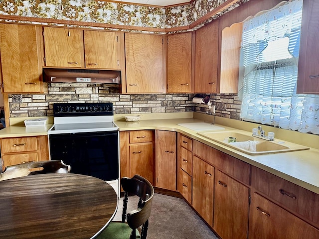 kitchen with light countertops, under cabinet range hood, a sink, and electric range
