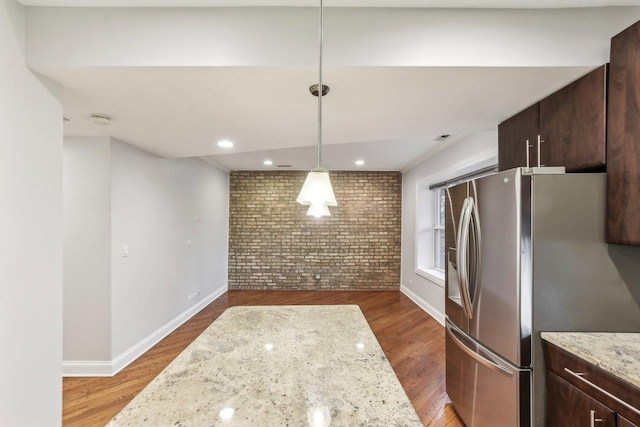 kitchen with dark brown cabinetry, brick wall, baseboards, and stainless steel refrigerator with ice dispenser