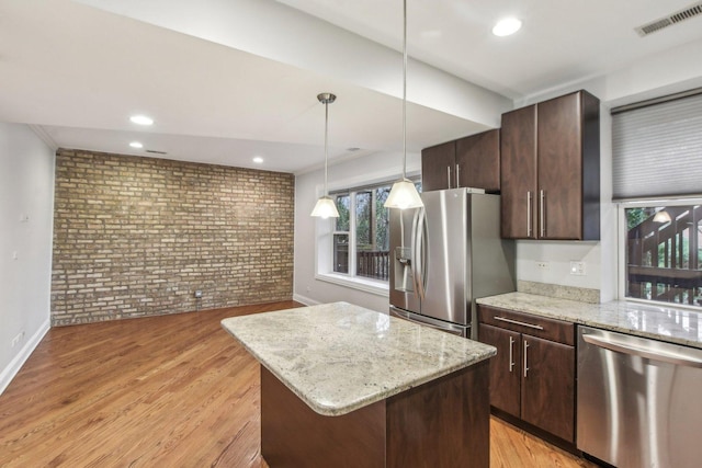 kitchen with visible vents, a center island, brick wall, dark brown cabinets, and stainless steel appliances