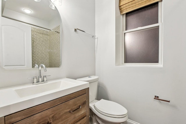 bathroom featuring toilet, a shower, and vanity