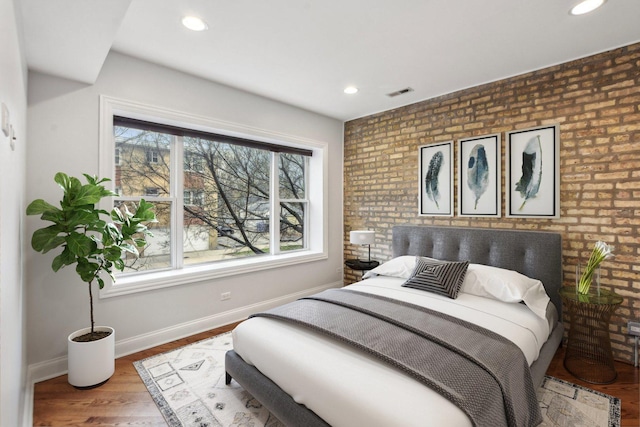 bedroom featuring baseboards, brick wall, recessed lighting, visible vents, and wood finished floors